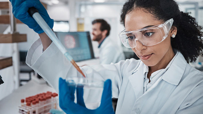 Scientist using a pipette to transfer liquid into a dish in a laboratory