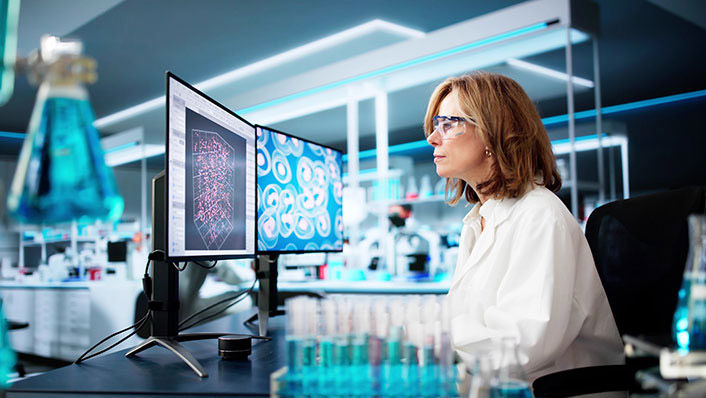 Image of a Woman infront of two computer monitors